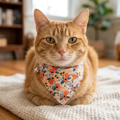 Bandana pour chat à fleurs oranges porté par un chat roux couché sur un tapis en laine