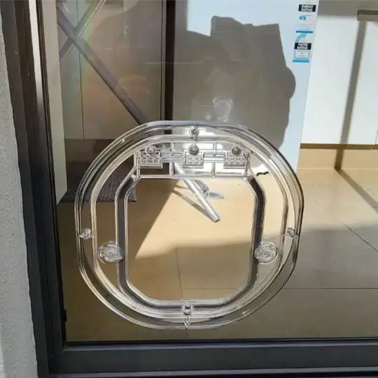 Chatière ronde transparente installée sur vitre coulissante aluminium