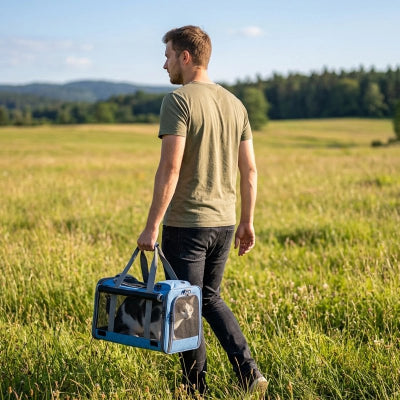 Homme portant un sac de transport pour chat bleu à travers un champ, promenade en pleine nature
