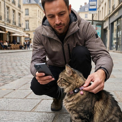 Homme regardant son téléphone tout en caressant un chat tigré portant un collier avec traceur GPS chat rose en ville