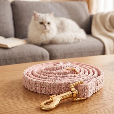Laisse pour chat rose doré posée sur une table en bois