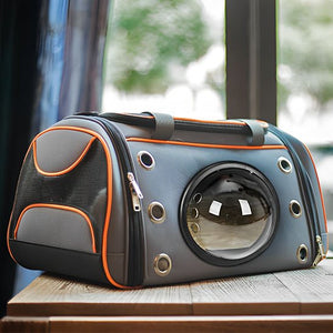 Sac de transport pour chat capsule spatiale gris et orange avec hublot transparent posé sur une table